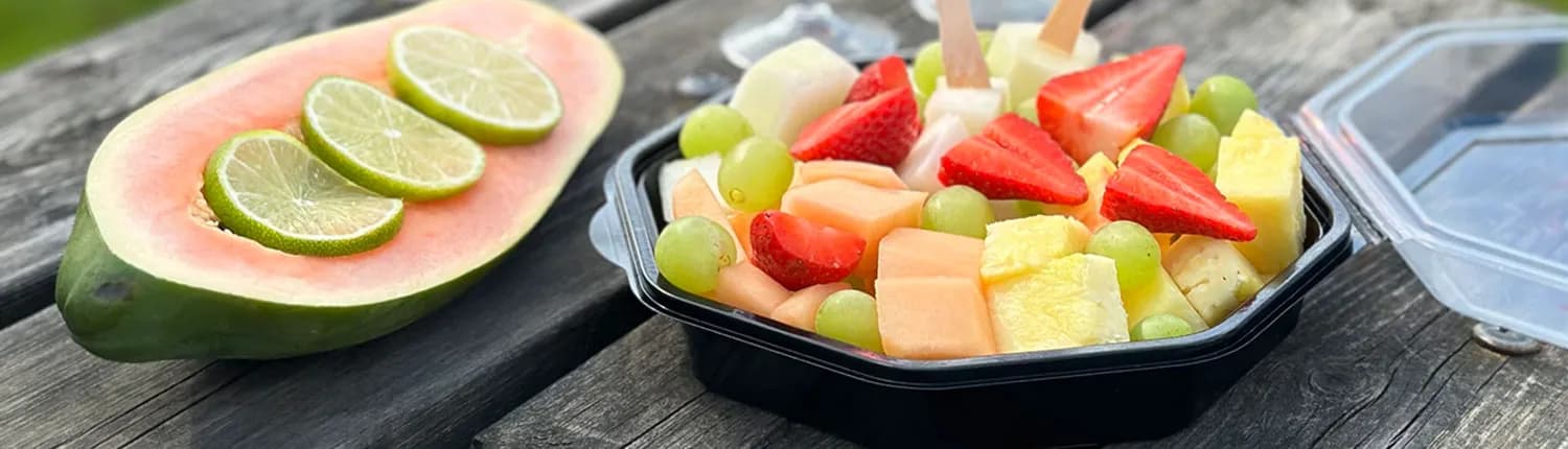 Healthy Snacks från HebeProduktion — fruktsallad med jordgubbar, druvor och ananas bredvid delad papaya