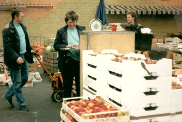 Bert, Birgitta och Roland Nilsson bland lådor med persikor och färskvaror på Partihallarna 1983