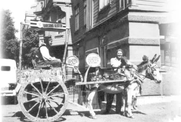 Två män med åsna och dekorerad vagn på en gata i Göteborg 1943