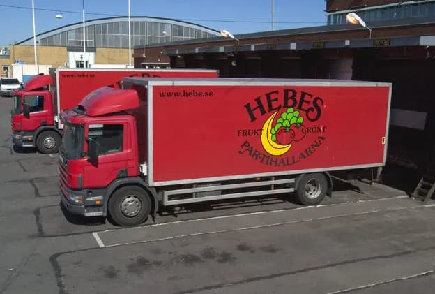 Röda Hebe-lastbilar med logotypen på skåpen står vid lastkajen på Partihallarna